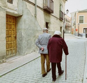 Two elderly people walking down the street